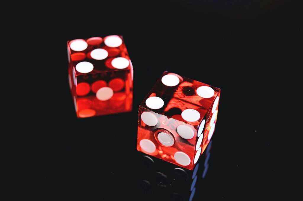 Close-up of two red dice on a shiny black background symbolizing luck and chance.